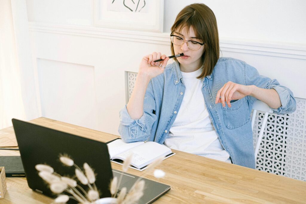 Woman thoughtfully thinking about what she's writing on a laptop