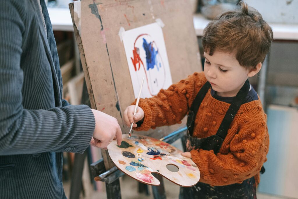 School volunteer helping a student paint.
