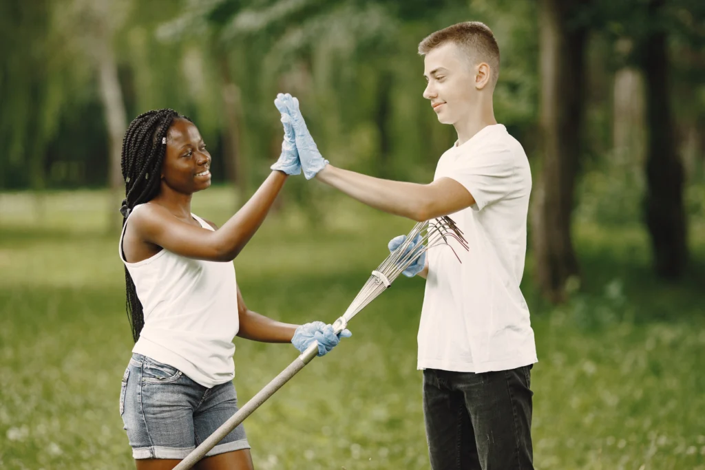 two people giving each other a high five with rubber gloves at a volunteering event