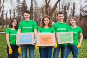 A group of young volunteers in matching green shirts and holding a donation Box