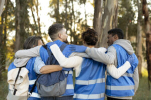 Four volunteers hugging each other and facing theit backs towards the camera.
