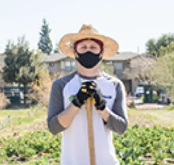 Volunteer at California Climate Action Corps holding gardening tool while working outdoors at community environmental project