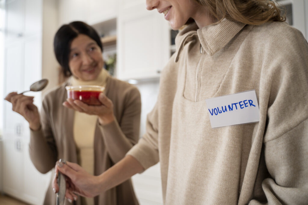 A women helping add ingredients to a dish a volunteer is cooking.