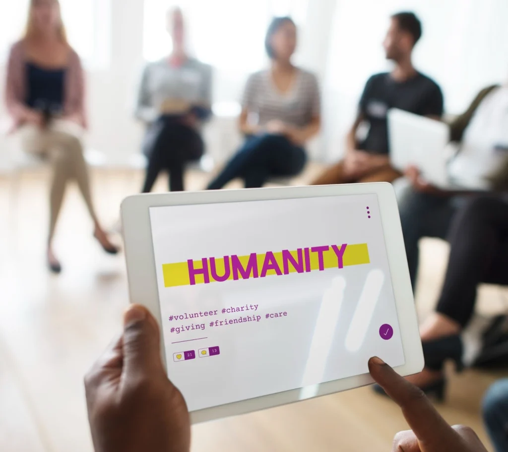 Nonprofit volunteer coordinator using a tablet to manage volunteer data integration during a team meeting