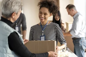 Two women handing off a box of donated good to each other.