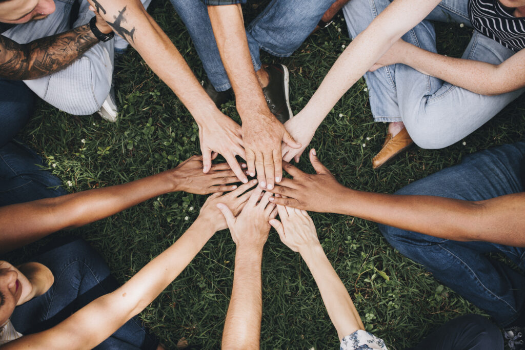 People stacking hands together in the middle of a group circle.