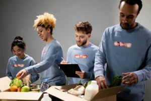 A group of volunteers organizing food boxes with their volunteer manager.